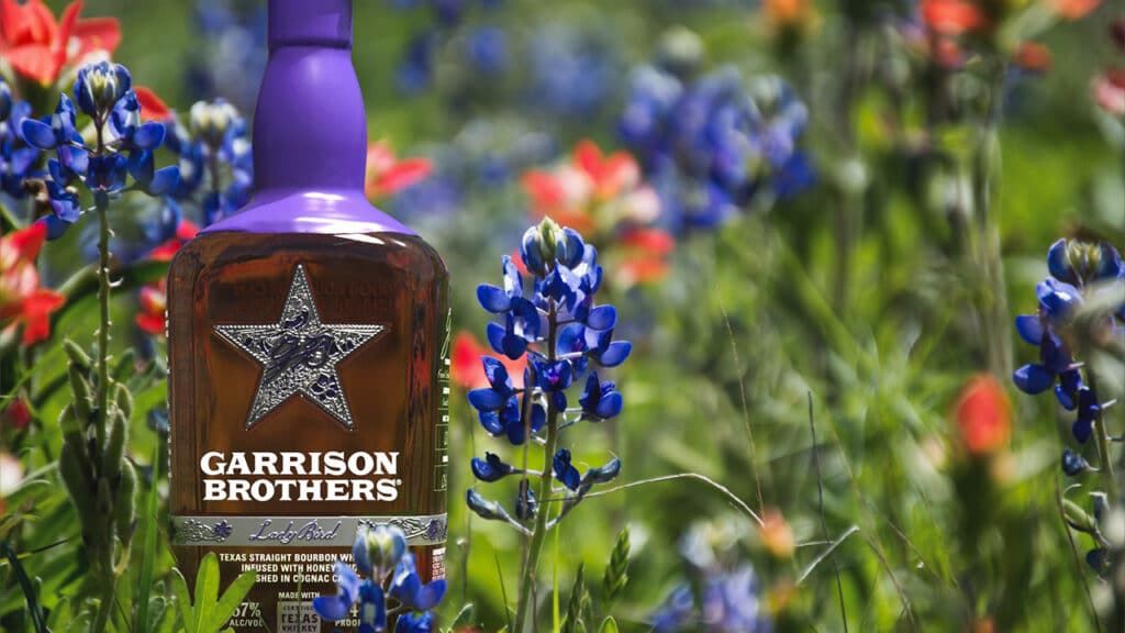 Garrison Brothers Lady Bird bottle in a field of Texas bluebonnets and Indian paintbrush